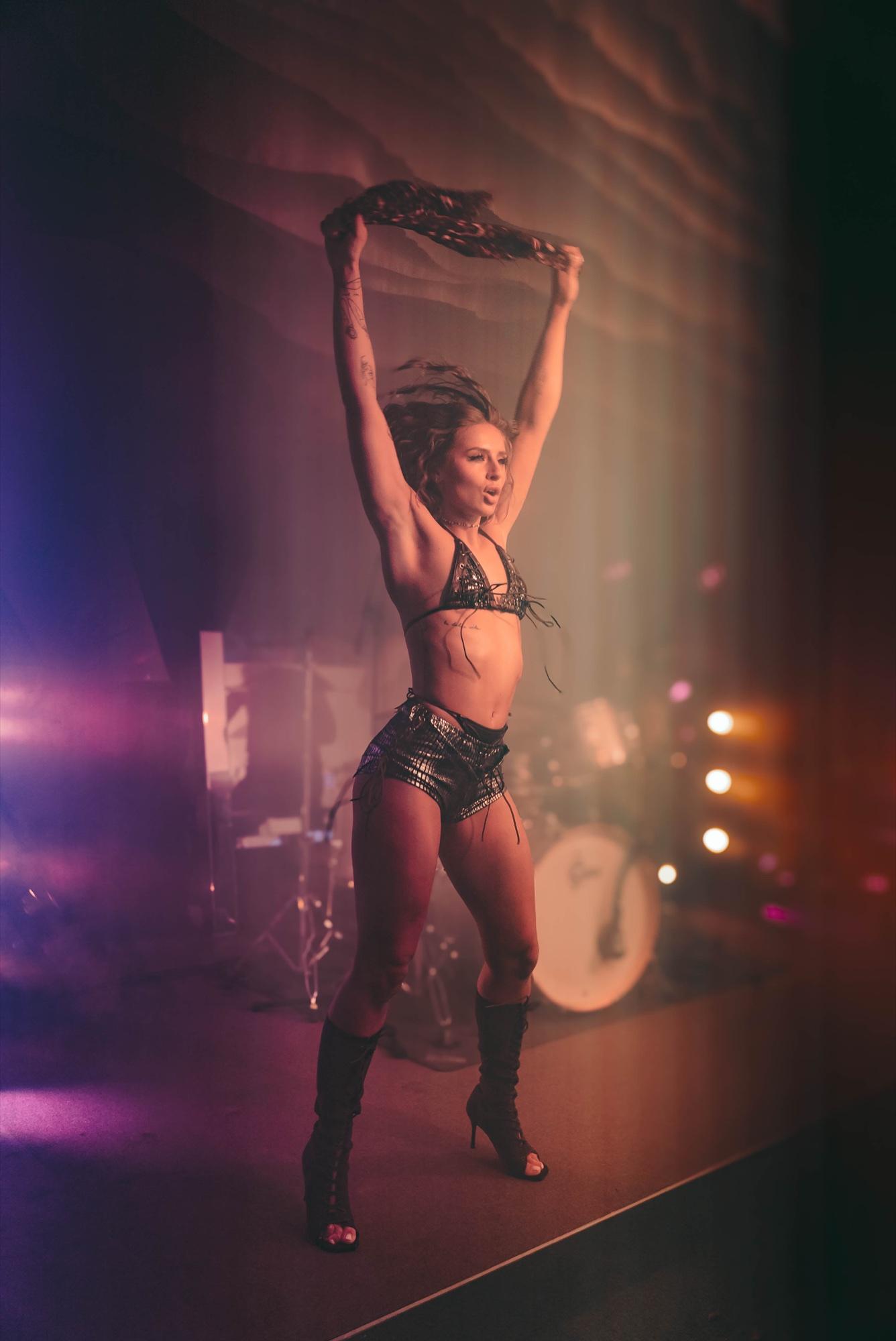 A solo dancer on stage in violet and pink light.