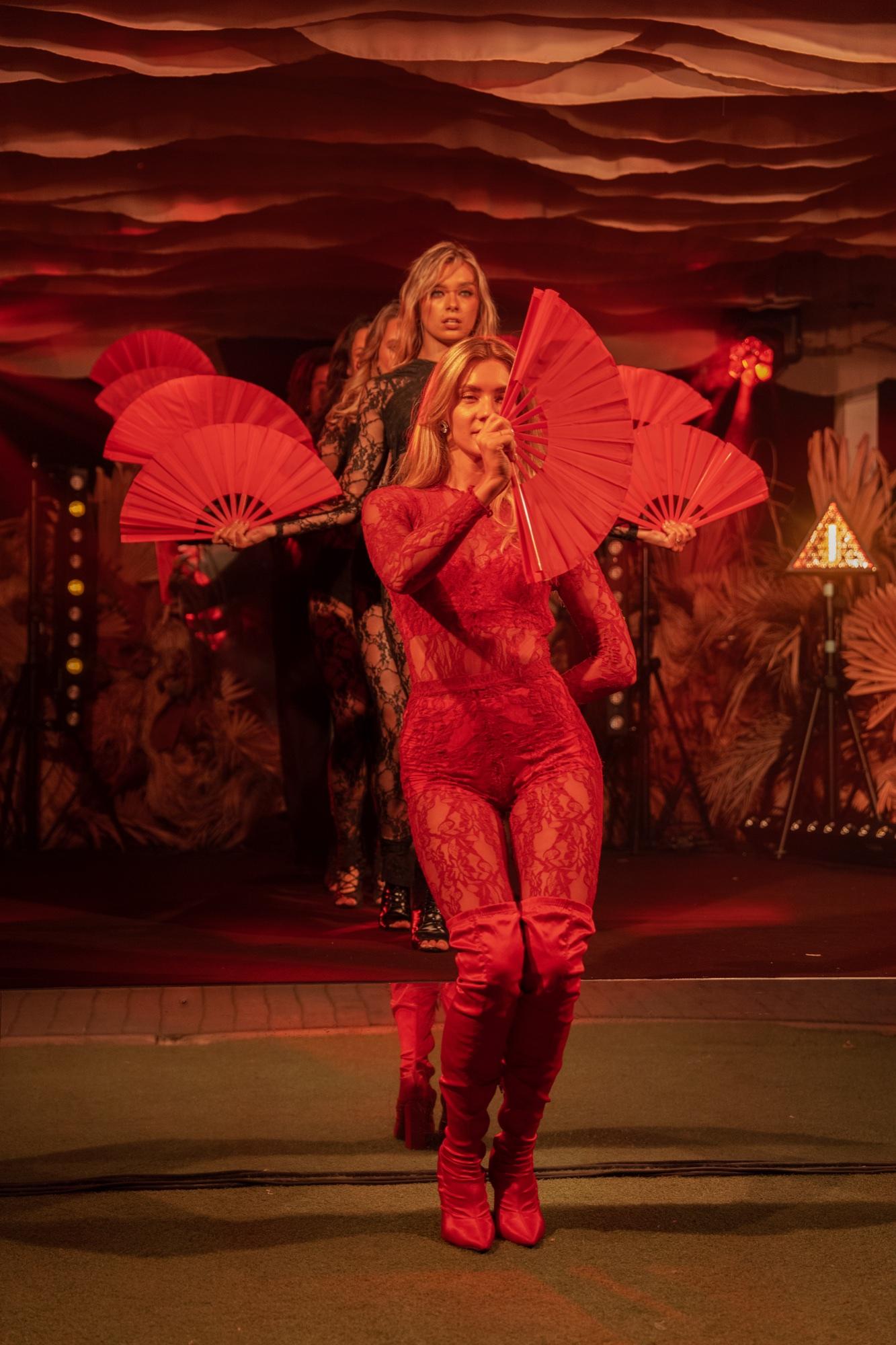 Performers in red costumes with red fans on stage.